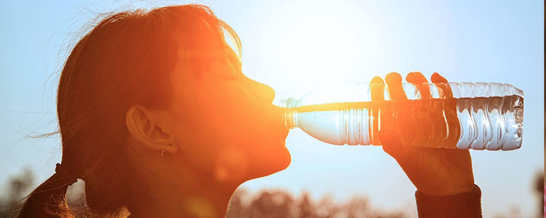 woman drinking from water bottle in sun